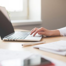 Person sitting at a table using a laptop.