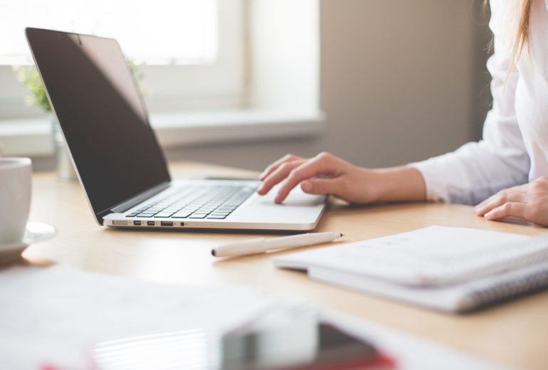 Person sitting at a table using a laptop.