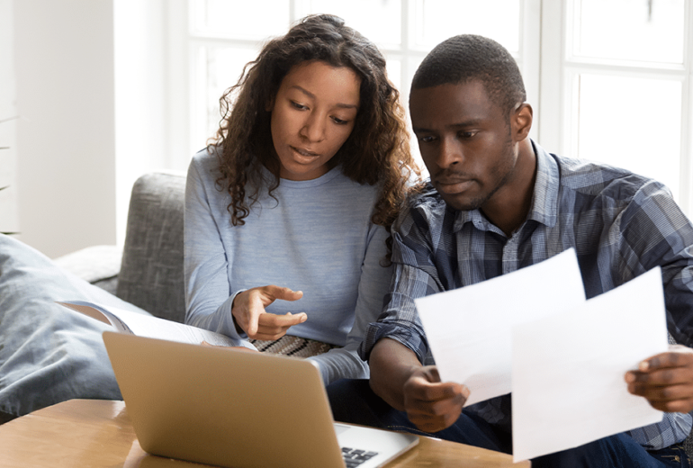 Couple using laptop to review finances.