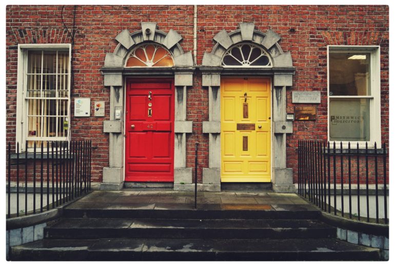 Two identical buildings with different colored doors.