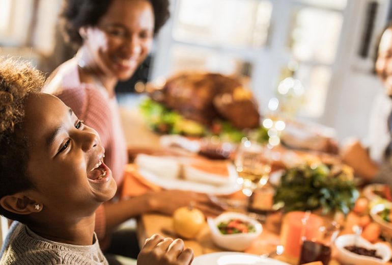 Cheerful African American girl with her parents at dining table.