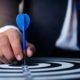Conceptual photo of a man in a suit holding a dart to a dartboard.