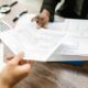 Hands sorting through financial documents on a wooden desk with a calculator nearby.