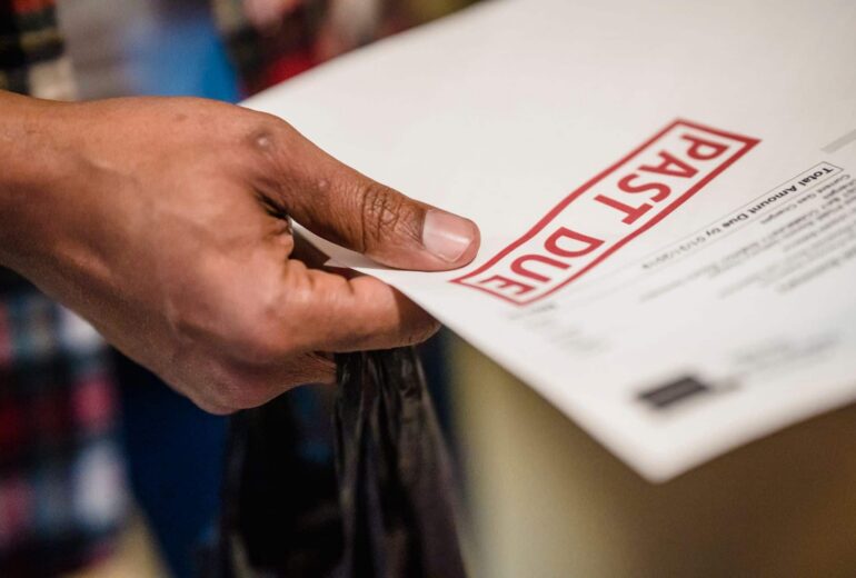 Close-up of a hand holding a white document with a bold red POST stamp partially visible on the page.